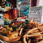 Delicious bacon cheeseburger with jalapenos and fries with drink.